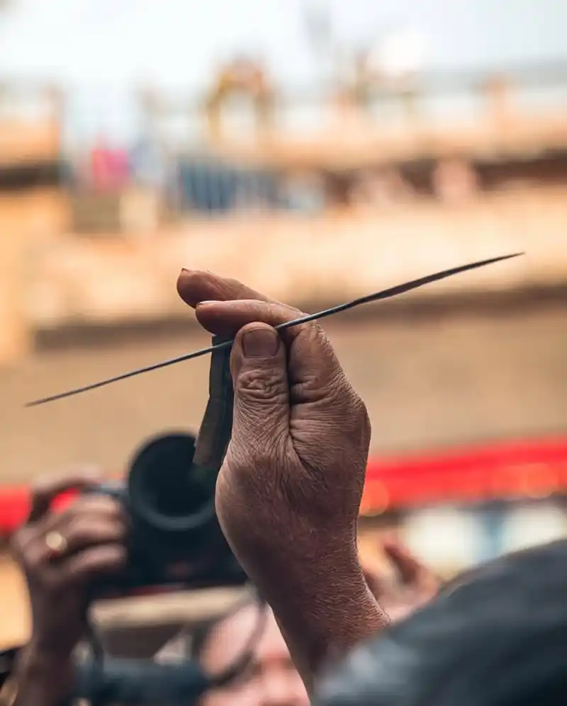 Hands holding a ritual stick during the Biska Jatra festival in Nepal.