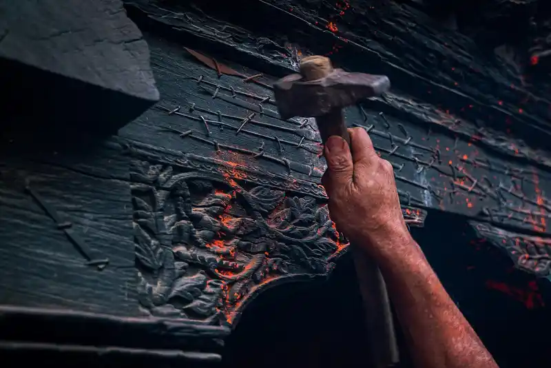 Man hammering a decorated wooden door during a Nepal cultural festival.