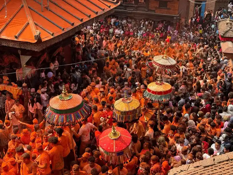 Crowd at Biska Jatra festival in Thimi, Nepal, featuring colorful ritual umbrellas.