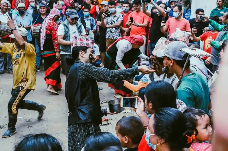 Crowd gathers at a Nepal cultural event, watching a man in yellow costume perform.