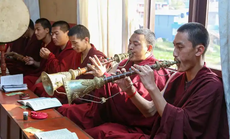 Monks playing traditional musical instruments during a cultural event in Nepal.