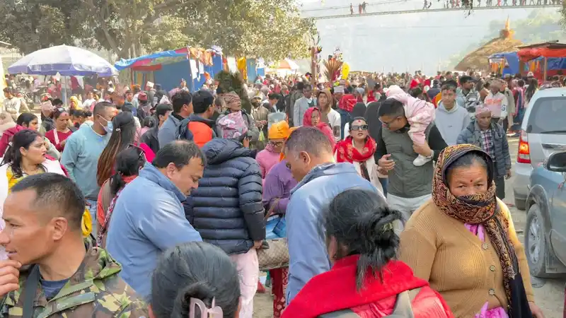 Crowd at a Nepal cultural festival, possibly Maghe Sankranti, with stalls and people gathered.
