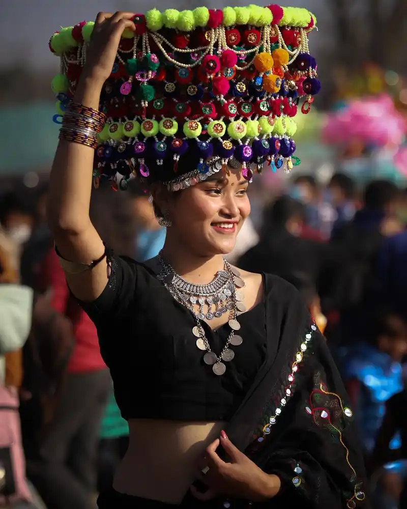 Nepali woman celebrating Maghe Sankranti with traditional Tharu festival attire and elaborate headpiece.