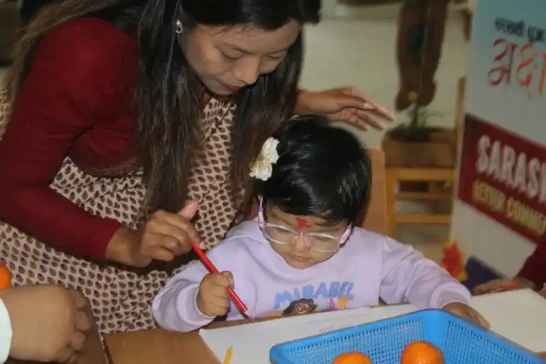 Mother helps child draw during Saraswati Puja Basanta Panchami celebration in Nepal.