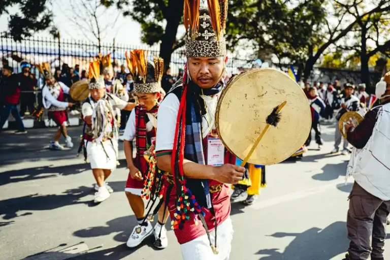 Nepali festival procession during Tamu Loshar, featuring men in traditional attire and ceremonial gongs.