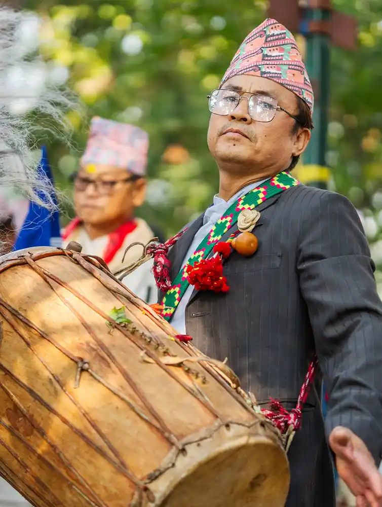 Kirat man celebrating Udhauli Parva in Nepal with traditional attire and drum.